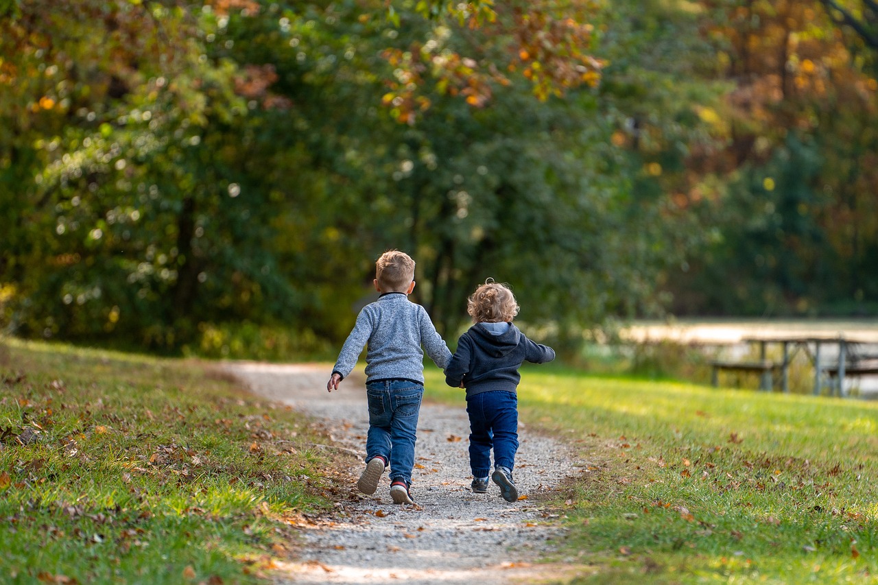 Zwei kleine Kinder laufen durch einen Park